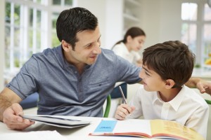 Father Helping Son With Homework Using Digital Tablet